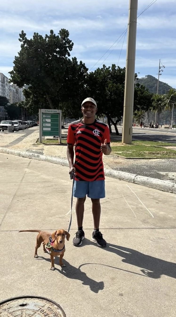 Breno com um dachshund na guia em frente à Praia do Leme